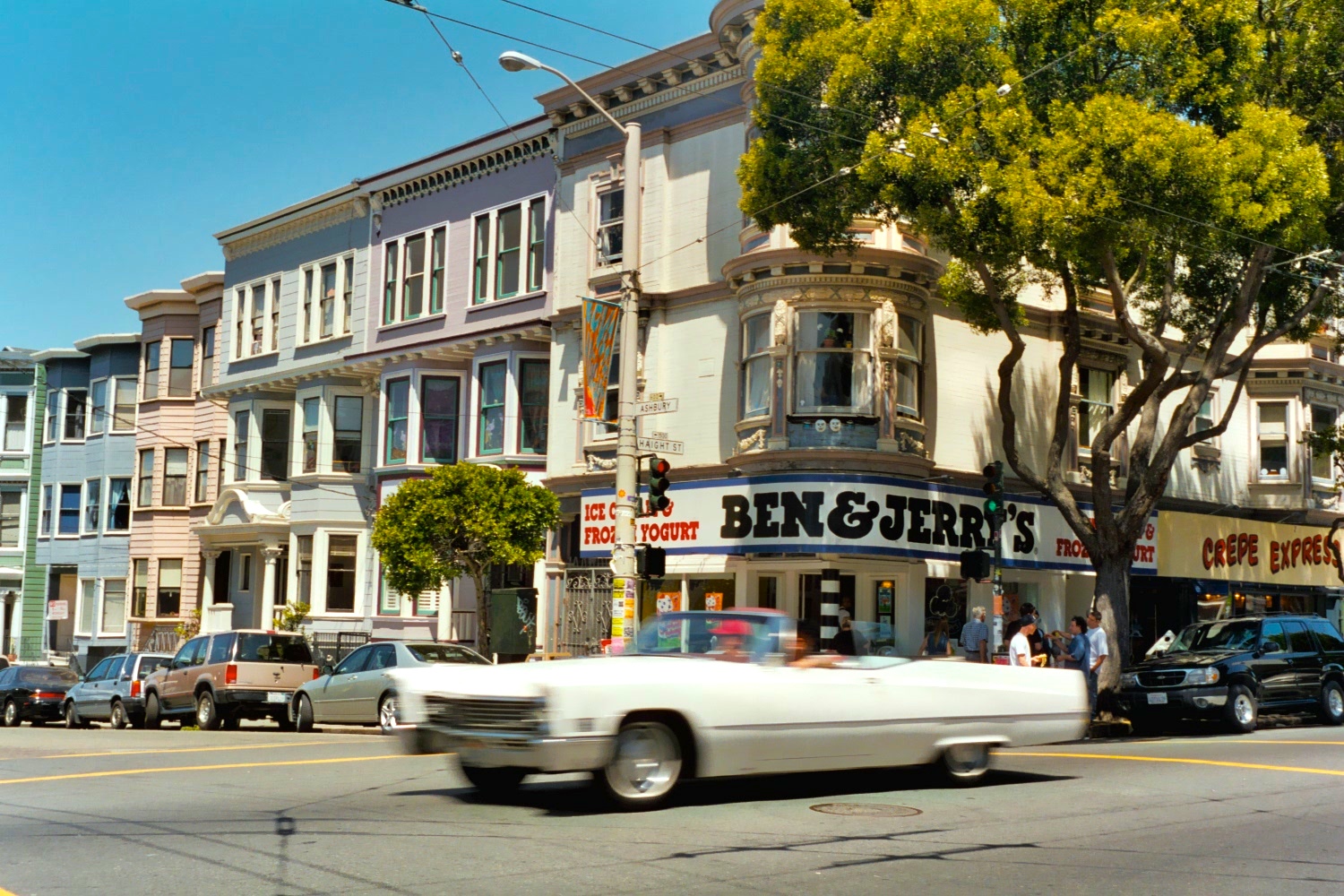 Haight-Ashbury street corner in San Francisco, with Ben & Jerry’s and a large, white cadillac convertible cruising through.