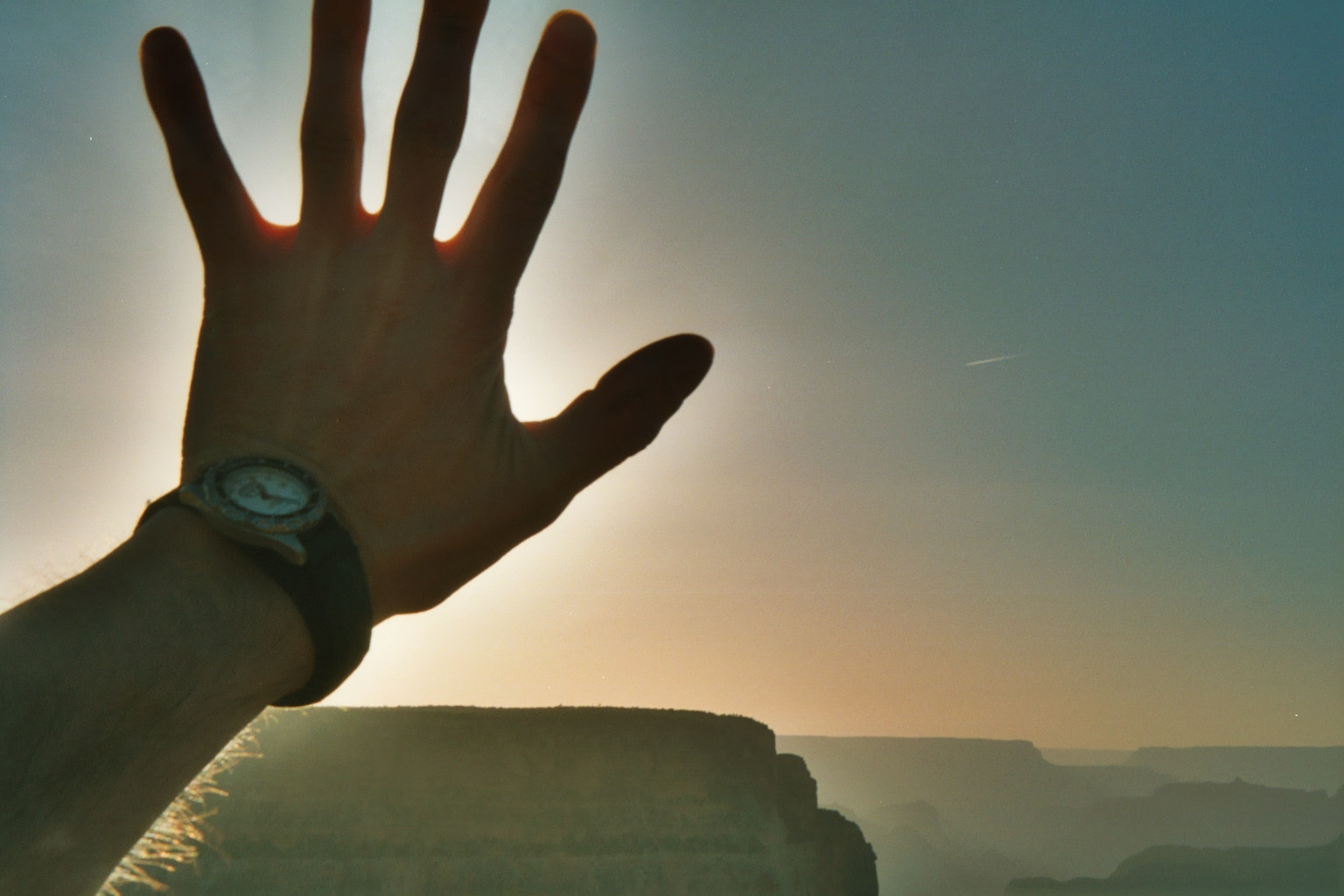 Simon: holding his hand in front of the sun with the Grand Canyon in the background.